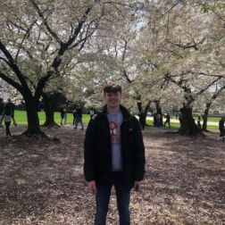 male student standing under cherry blossom trees in the US